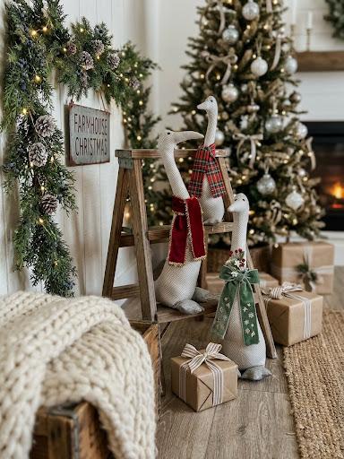 Handmade fabric geese in tartan scarves and ribbons beside a Christmas tree and wrapped gifts